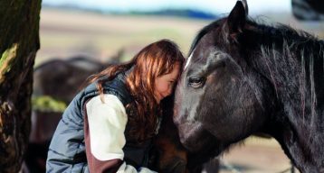 Stock image of a child bonding with a horse, pressing their foreheads together