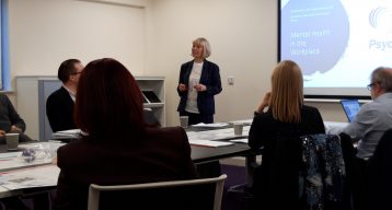 Photograph of Julie Stirpe delivering a presentation to the room